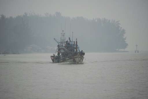 A fishing boat sails through haze on the Narathiwat River in southern Thailand