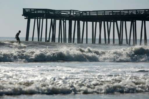A man surfs near the Virginia Beach Fishing Pier, which suffered damage from Hurricane Irene, on August 28, 2011 in Virginia Bea