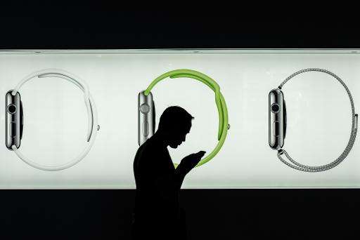 A man uses a smartphone in front of an Apple store display advertising the Apple watch in Hong Kong
