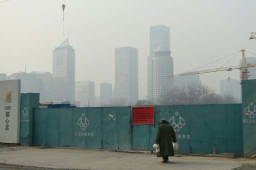 A man walks towards a &quot;red alert&quot; pollution notice announcing the suspension of outdoor work, on an entrance to a clos