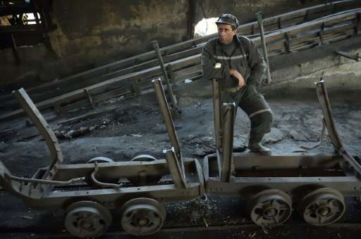 A miner next to mining carriages as he waits for the last shift at the coal mine in the Romanian city of Petrila, on October 30,