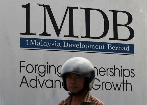 A motor cyclist rides past a hoarding at the construction site of the 1 Malaysia Development Berhad (1MDB) flagship Tun Razak Ex
