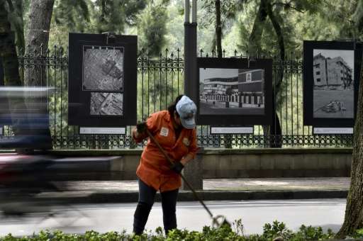 A municipal worker in Mexico City on September 17, 2015  cleans in front of pictures of the damage caused by the September 19, 1