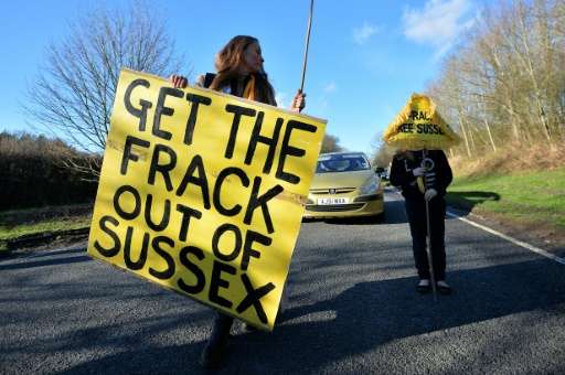 An anti-fracking and climate protester holds a placard during a rally at the former test drill site operated by British energy f