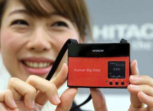 An employee from Japanese electronics giant Hitachi shows a wearable sensor aimed at measuring the happiness of workers