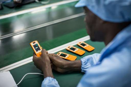 An employee works on a mobile phone on an assembly line in Brazzaville on July 20, 2015