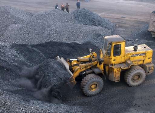 An excavator moves coal onto a truck at a port in Yichang, central China on March 11, 2014