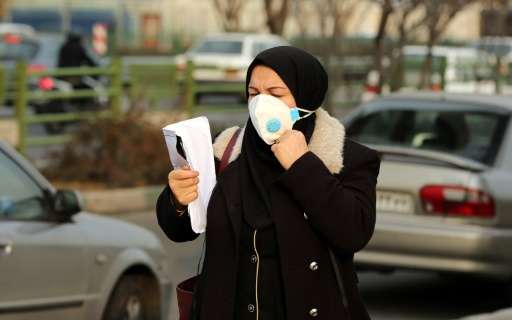 An Iranian woman wears a facemask as she walks in a heavily polluted area in Tehran on December 19, 2015 as the capital city's a