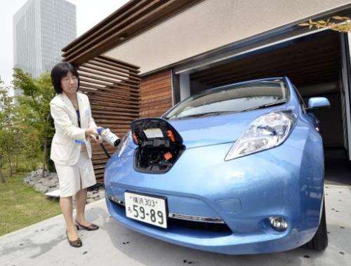 A Nissan employee demonstrates charging one of the country's Leaf electric vehicles using a smart home electricity supply cable 