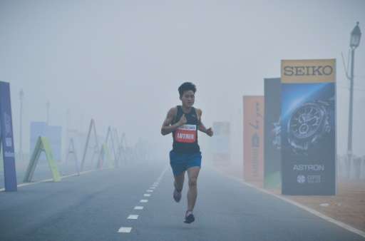 A participant runs through smog on Rajpath during the Airtel Delhi Half Marathon 2015 in New Delhi on November 29, 2015