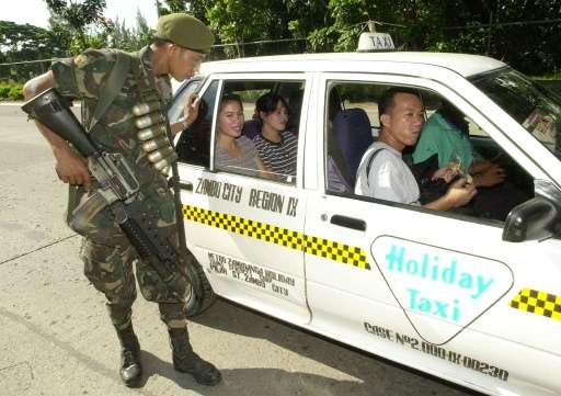 A Philippines policeman inspects a taxi at a checkpoint in Zamboanga City