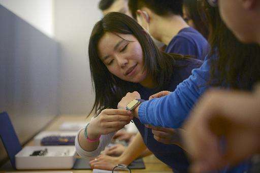 Apple staff help customers to try on the new Apple Watch at a store in Beijing on April 10,2015