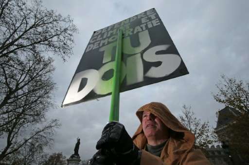 A protestor dressed in reference to Star Wars holds stands in front of a sign reading &quot;Defend climate and democracy, you mu