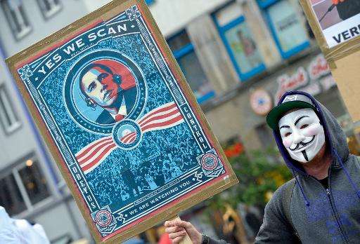 A protestor wearing a Guy-Fawkes-mask holds a banner with a picture of US President Barack Obama to protest against the NSA inte