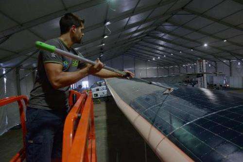 A support team member cleans the solar panals on the wings of Solar Impulse 2, the world's only solar powered aircraft, at Sarda