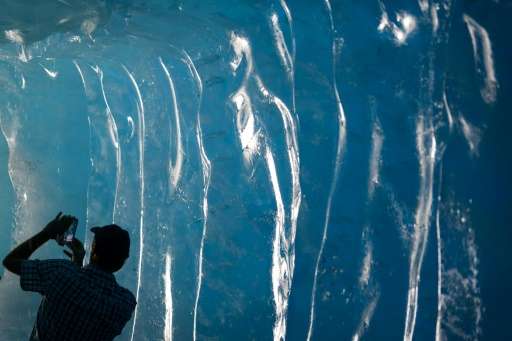 A tourist takes pictures inside an ice cave inside the Rhone Glacier near Gletsch