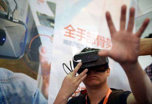 A visitor tries on virtual reality glasses from Oculus Rift Development Kit 2 during the first Consumer Electronics Show in Asia