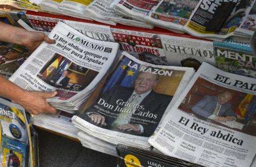 A woman arranges special editions of Spanish newspapers in Madrid on June 2, 2014 following the announcement by King Juan Carlos