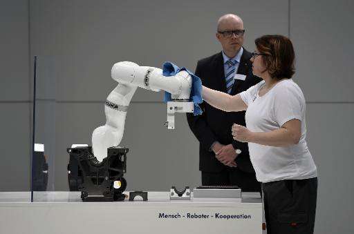 A woman cleans a robot on display at the booth of German car maker Volkswagen (VW) at the Hannover Messe industrial trade fair i