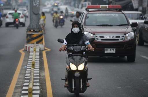 A woman rides her motorcycle through thick haze in Narathiwat, southern Thailand on October 5, 2015