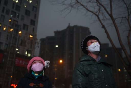 Beijing residents watch a giant video screen outside a shopping mall on a polluted day, on December 9, 2015