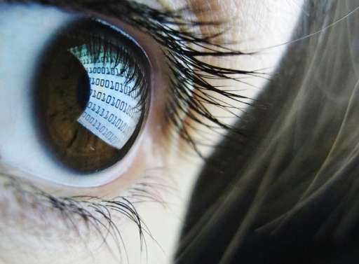 Binary code is reflected from a computer screen in a woman's eye