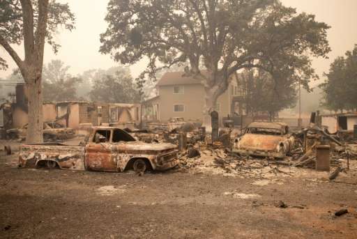 Burned out vehicles are surrounded by smoldering rubble while firefighters continue to battle the Valley fire in Middletown, Cal