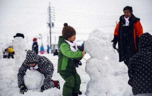 Children make snowmen in Iiyama city, Nagano prefecture on February 15, 2015