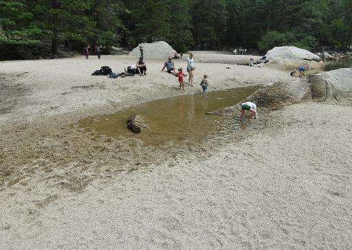 Children play on the exposed sandy bottom of Mirror Lake that is normally underwater and used by visitors to photograph reflecti