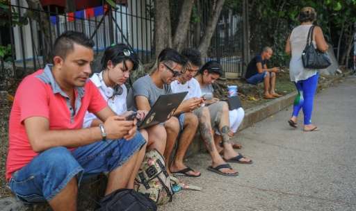 Cubans use their mobile devices to connect to the Internet via wifi in a street of Havana, on July 2, 2015