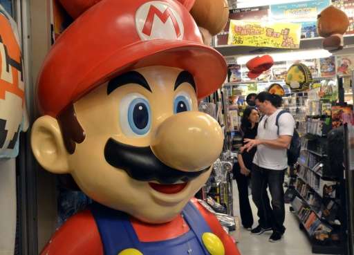 Customers check used videogame consoles and software, at a shop 'Super Potato' in Tokyo
