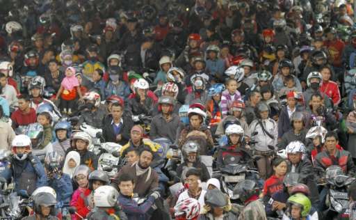 Hundreds of Indonesian passengers on motorcycles wait to board a ferry at Merak port in western Java island on July 15, 2015 to 