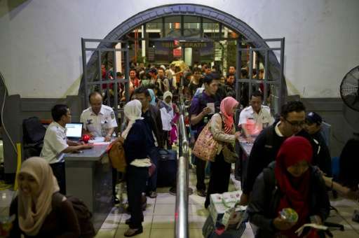 Indonesian passengers enter the departure area of a packed train station in Jakarta on July 14, 2015