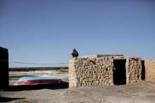 Iranian boys sit on the roof of a mud-house in the village of Adimi situated in the once exceptional wetlands of Lake Hamoon, no