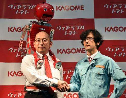 Kagome employee Shigenori Suzuki (L) wears the tomato dispenser, which was developed by Japanese artist Nobumichi Tosa (R)
