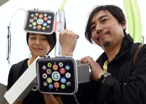 Makoto Saito (L), wearing a giant cardboard Apple Watch on her head, poses with a friend after buying the new watch at a telecom