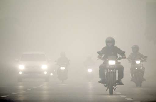 Motorists travel under a heavy blanket of haze in Palangkaraya, on Indonesia's Borneo island, on October 12, 2015