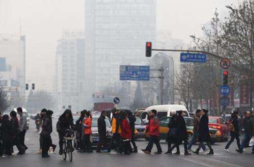 Pedestrians cross a road on a polluted day in Beijing on December 9, 2014