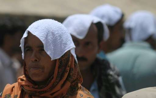People are seen covering their heads with wet towels during a heatwave in Karachi, Pakistan, on June 29, 2015