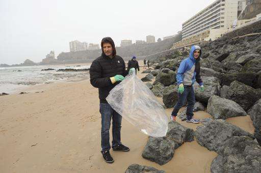 People collect waste  on a beach in Biarritz, France during the launch of a weekend of voluntary cleanup, called Initiatives Oce