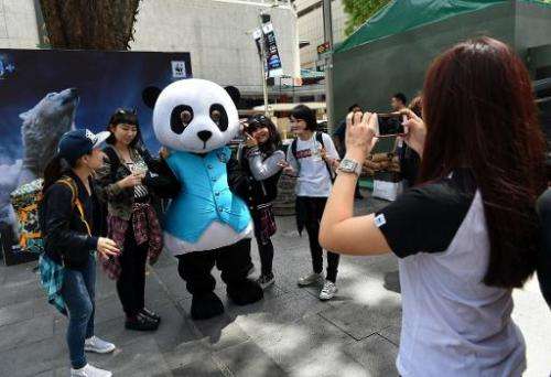 People in Singapore on March 12, 2915 pose with a WWF (World Wide Fund For Nature) panda mascot promoting Earth Hour