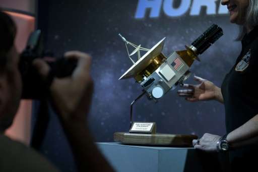 People pose with a model of the New Horizons probe at the Johns Hopkins University Applied Physics Laboratory July 14, 2015 in L