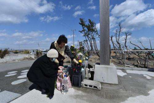 People pray for victims of the 2011 quake-tsunami disaster at a cenotaph in the coastal area of Arahama district in Sendai, Miya