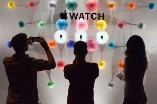 People stand before a window display of the Apple watch during the unveiling of the new and highly anticipated product at Saint-