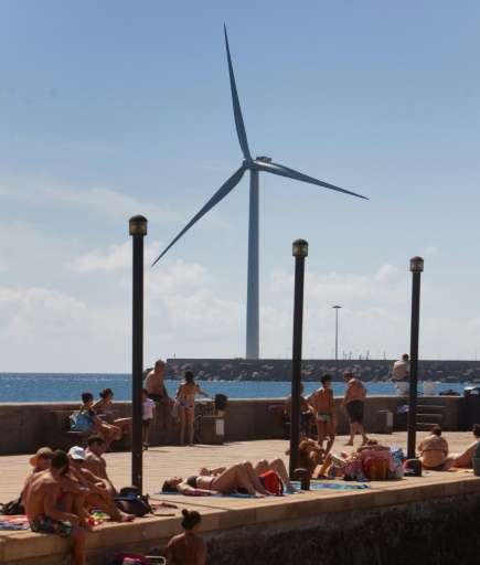 People sunbathe near Spain's largest wind turbine, a 154 m tall 5 mw installation in Arinaga port on Gran Canaria