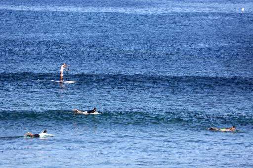 People surf off the coast of Trois Bassins on the western coast of the French Indian Ocean island of La Reunion on April 17, 201