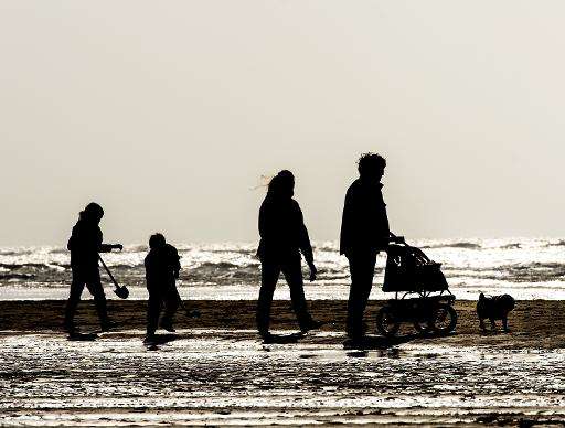 People walk along the beach at Egmond aan Zee on March 8, 2015, in the Netherlands