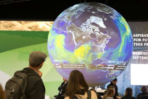 People watch the Earth globe at the COP21, the United Nations conference on climate change, in Le Bourget on December 10, 2015