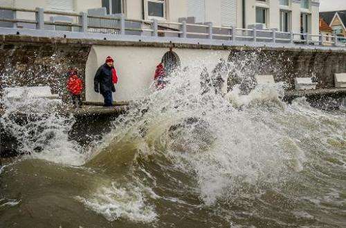People watch waves crashing onto the Wimereux waterfront, northern France, on February 21, 2015