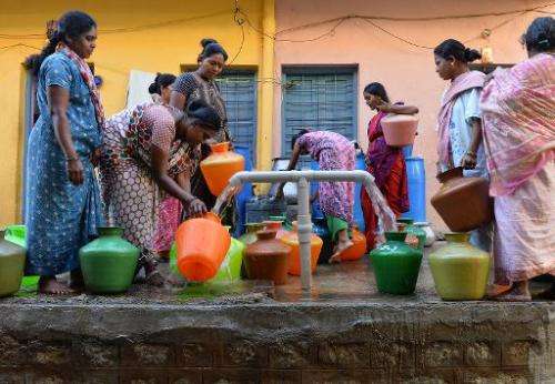 Residents in Bangalore wait to collect drinking water in plastic pots for their households on March 18, 2015